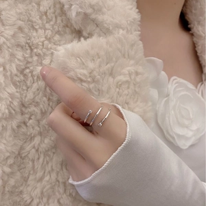 Detail of silver triple-band ring with zircon stones on model hand with flowers
