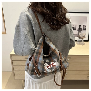 Plaid tote bag with cute puppy patch and brown leather strap shown in use