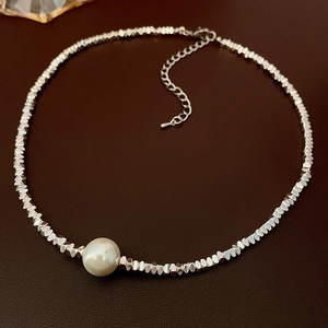 Detail of irregular silver beads and large white freshwater pearl on a beaded necklace