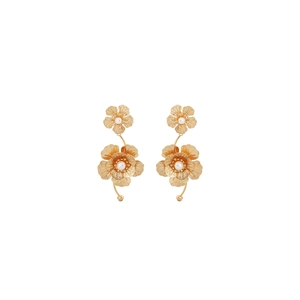 Detailed close-up of golden floral earrings with white pearls and layered metal petals