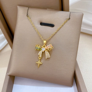 Macro detail of gold bow necklace with colorful zircons and star pendant in a gift box