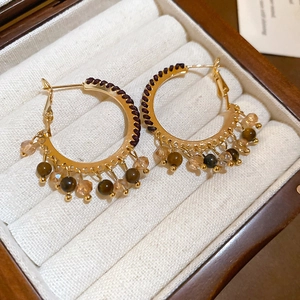 Detail of bohemian gold hoop earrings with brown beads and crystals in a velvet jewelry box