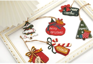 Macro detail of hand-painted wooden Christmas tree and gift bag ornaments with rustic rope