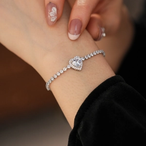 Detailed view of silver heart tennis bracelet with micro-pave zircons on woman's wrist