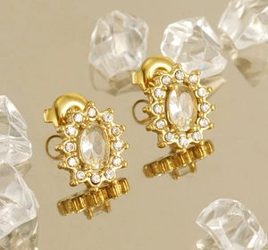 Macro shot of gold-plated double-layer earrings with sparkling crystals on a reflective surface