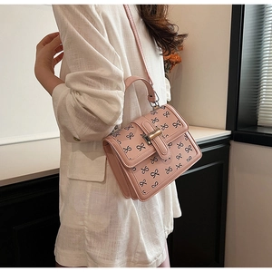Borsa a tracolla rosa con motivo a fiocchi neri e chiusura dorata indossata da modella