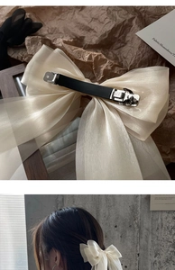 Detail of elegant beige organza bow hair clip with metal spring clasp for women's hairstyle
