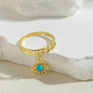 Detail of adjustable gold chain ring featuring a turquoise evil eye charm on stone