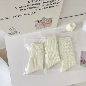 Detail view of three cream cotton socks featuring teddy bear lace and mesh textures