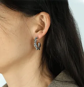 Close-up of a silver twisted hoop earring showing intricate woven metal texture and shine