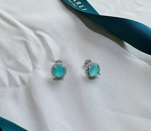 Macro shot of 925 silver halo stud earrings with round paraiba green gemstones