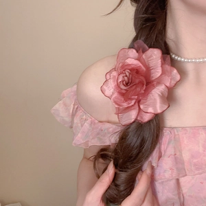 Detail of pink organza flower hair clip styled on a dark braided hairstyle for vacation