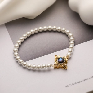 Detail eines Perlenarmbands mit goldenem Vintage-Verschluss und irisierender Muschel