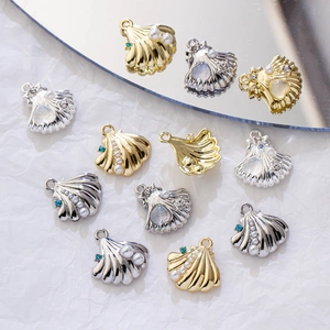 Detailed view of gold and silver shell pendants with pearls on a white silk background