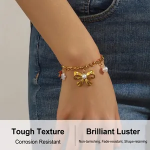 Détail d'un bracelet nœud doré avec perles et étoiles porté au poignet sur fond de jean