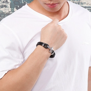 Détail macro d'un bracelet en cuir tressé noir pour homme avec fermoir ancre argenté