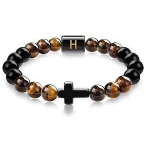 Macro detail of Tiger Eye beaded bracelet with black cross and golden H letter charm