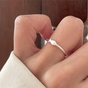 Vista macro dell'anello a forma di pesce in argento minimalista indossato al dito, lucido