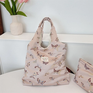 Detail of pink butterfly jacquard shoulder bag with matching zipper pouch on white surface