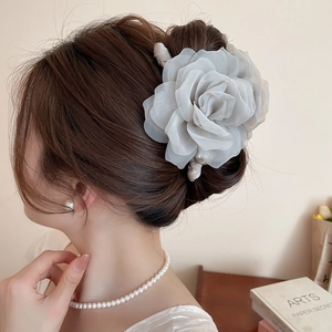 Vue détaillée d'une pince à cheveux rose en organza gris élégante sur un chignon