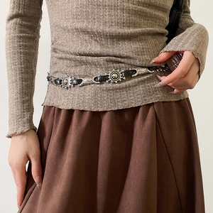 Close-up of bohemian leather belt featuring silver sunburst metal medallions on model