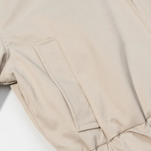 Detailed close-up showing the precise stitching and side pocket of the beige cotton jacket