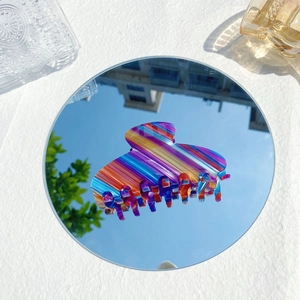 Vue détaillée d'une pince à cheveux en acétate avec rayures colorées et reflet miroir