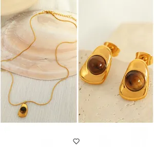 Detail of gold titanium steel jewelry set with brown gemstones on shell background