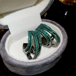 Close-up of multi-layer C-shaped earrings with green cubic zirconia pave setting