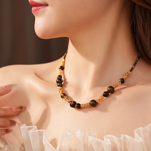Détail du collier de perles œil de tigre doré sur le cou d'un mannequin femme