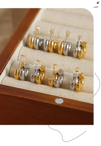 Detailed view of bicolor gold and silver C-shaped hoops on a linen jewelry display box