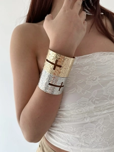 Close-up of gold and silver cross hollowed textured cuffs on model's wrist