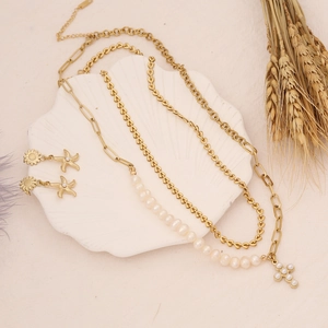 Detail of pearl cross necklace and starfish earrings set on white seashell tray