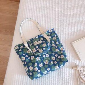 Detailed shot of dark blue floral cotton tote bag with white flower patterns on a bed