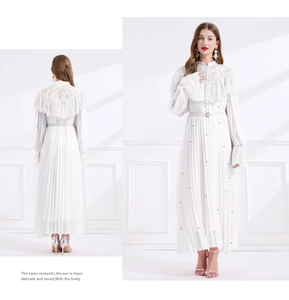 Détail d'une robe plissée en dentelle blanche avec ceinture en perles portée par un modèle