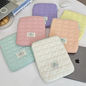 Detail of heart-quilted laptop sleeves in six macaron colors with Happy woven label