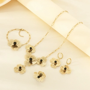 Flat lay of vintage gold floral jewelry set with black bead accents on silk backdrop
