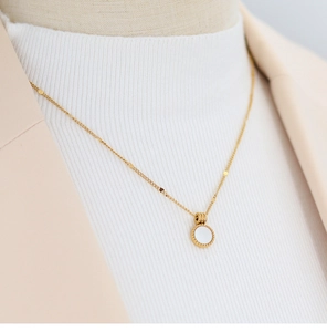 Close-up of a 18K gold plated titanium necklace with a white mother of pearl shell pendant