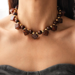 Detailed close-up of leopard print acrylic cubes and dark wooden beads on vintage necklace