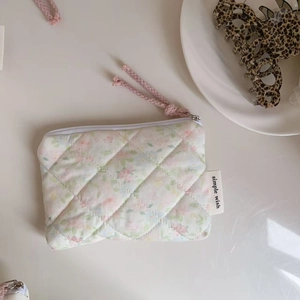 Close-up of a floral quilted mini pouch with a zipper and 'simple wish' side label