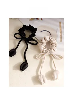 Close-up of premium satin tulip ribbon hair scrunchies in black and cream beige