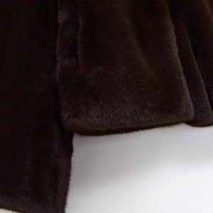 Détails de l'ourlet et de la manche d'une veste en fausse fourrure marron sur fond gris