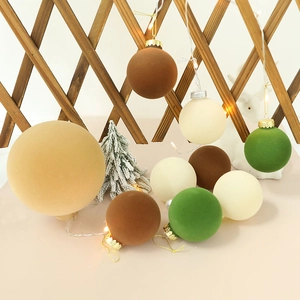 Set of flocked Christmas ornaments in earth tones on a rustic fence with warm LED lights