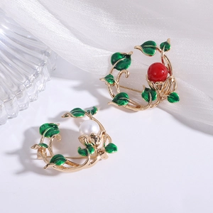 Detail of floral vine brooches with green enamel leaves, red bead and white pearl accents