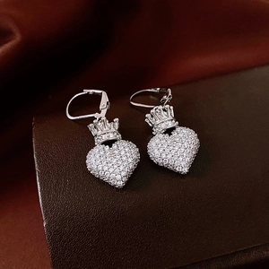 Détail de boucles d'oreilles cœur couronne argentées serties de zircons sur cuir brun