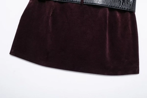 Détail de la jupe en velours bordeaux et ceinture noire avec motif crocodile