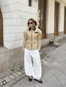 Detail of khaki jacket with black leather trim and structured shoulder padding design