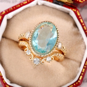 Ensemble de bagues couronne dorées avec une gemme ovale bleu clair sur écrin rouge