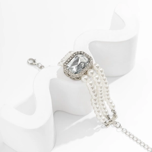Detailed macro view of triple-strand pearl bracelet with emerald-cut crystal centerpiece