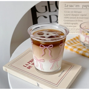 Detail of transparent glass cup with pink bow pattern and layered coffee drink inside